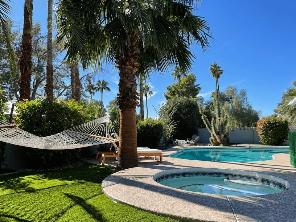 Backyard with pool, hammock, and palm trees on a sunny day.