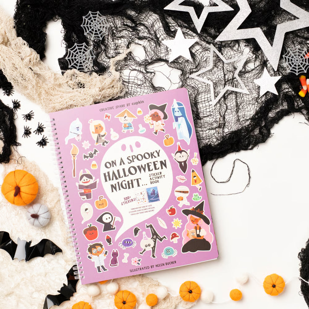 Halloween-themed sticker book surrounded by decorative items on a white background