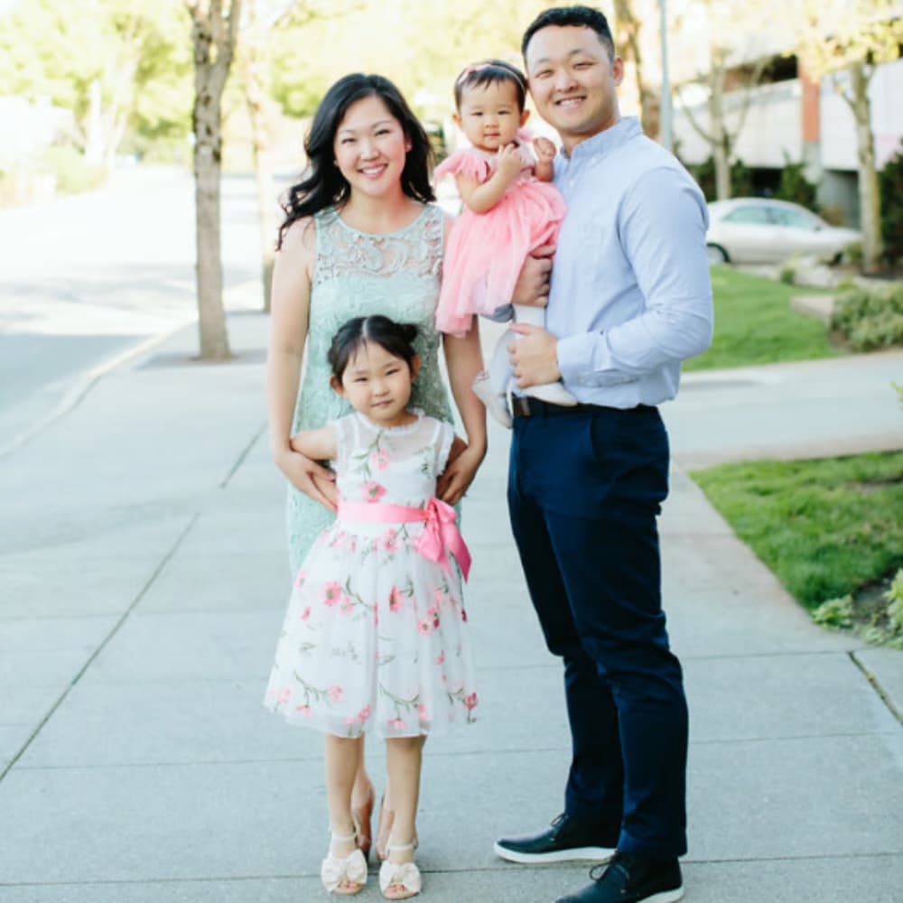 Family of four standing on a sidewalk in a suburban neighborhood