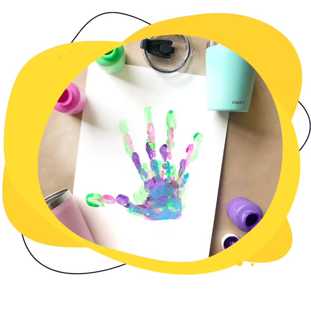 Colorful handprint on a white shirt with paint bottles and a stethoscope in the background.